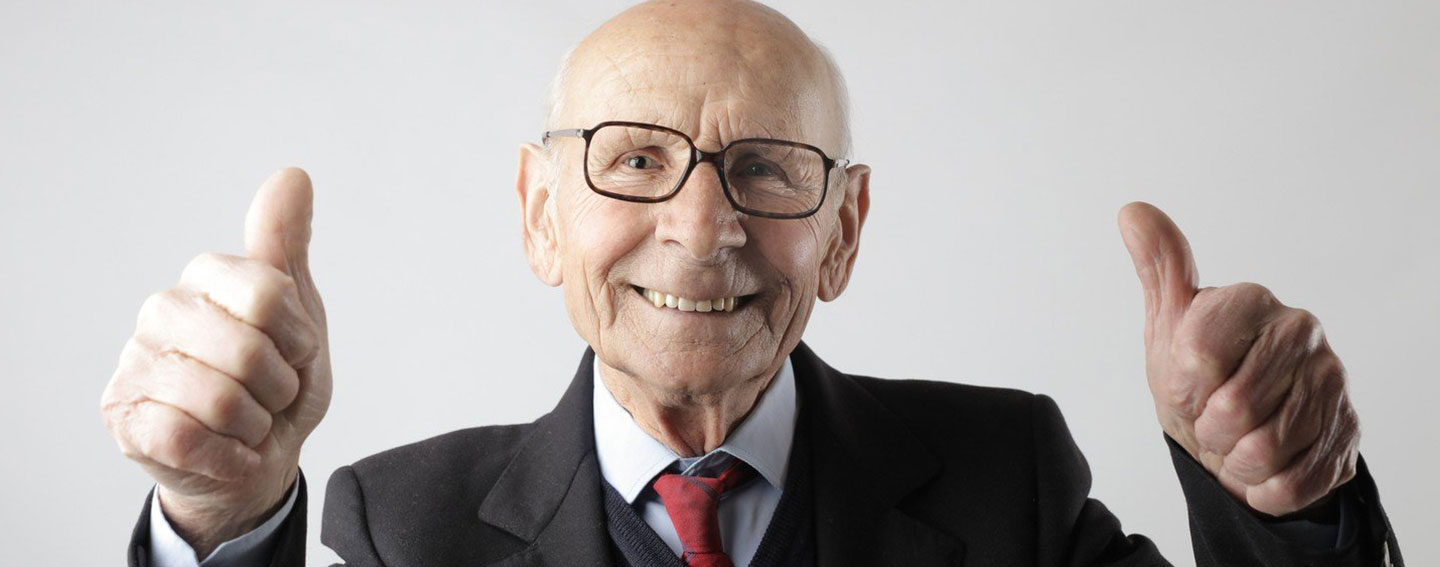 ein alter Mann zeigt lächelnd beide Daumen hoch in die Kamera